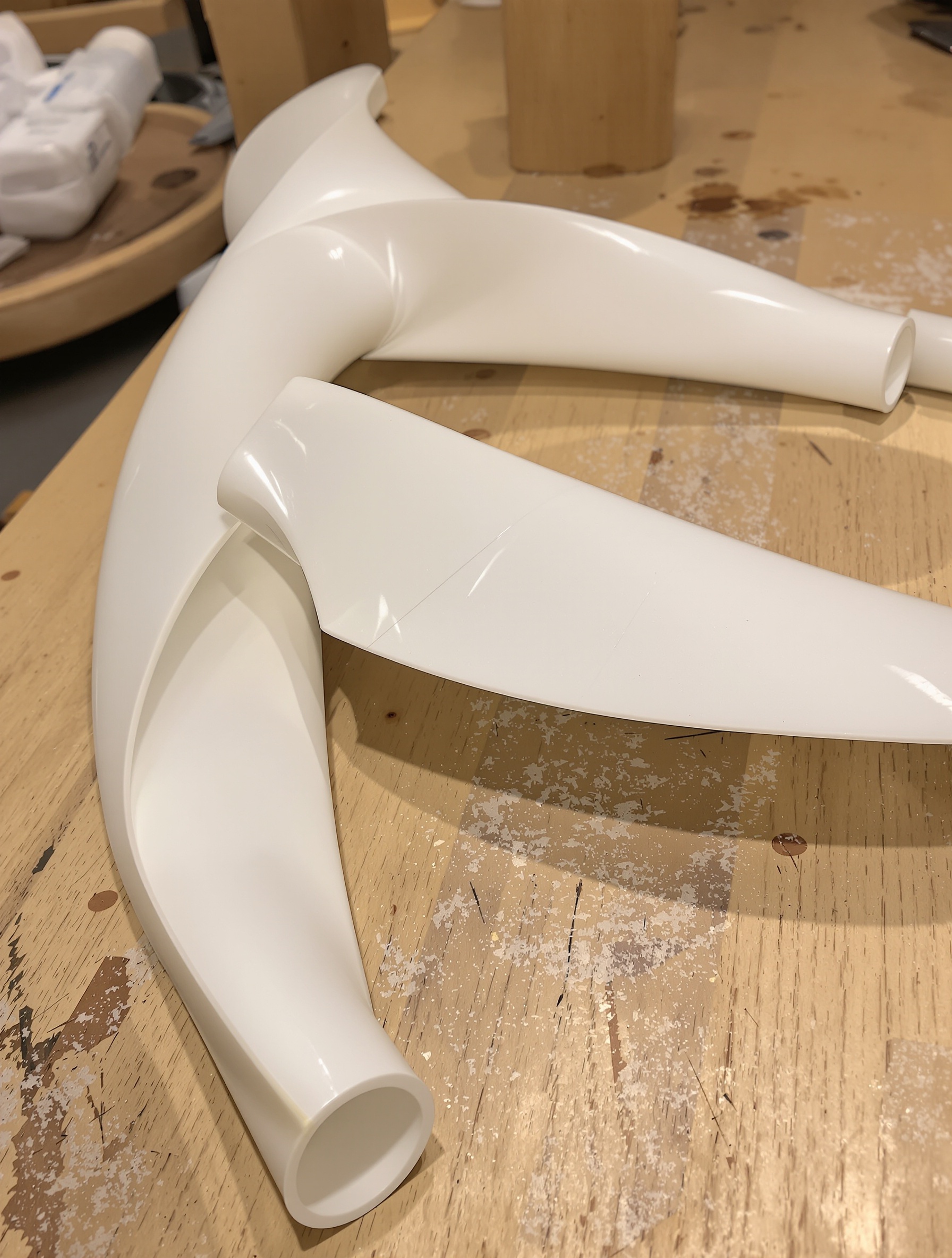 Trois pales d'éolienne DIY fraîchement découpées dans un tube en PVC blanc sur un établi en bois