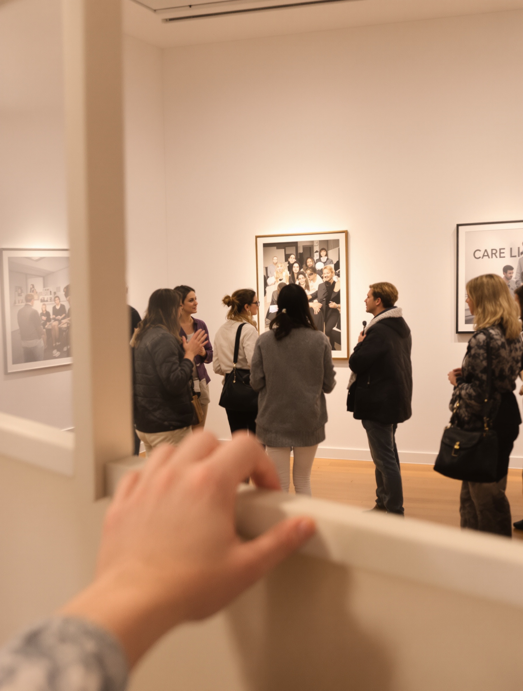 Atmosphère chaleureuse avec des visiteurs en discussion dans une galerie contemporaine, Marais, Paris